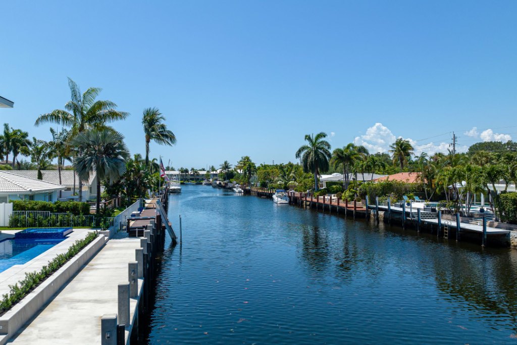 A palm-lined residential canal in Lighthouse Point, with docks and waterfront homes along both banks